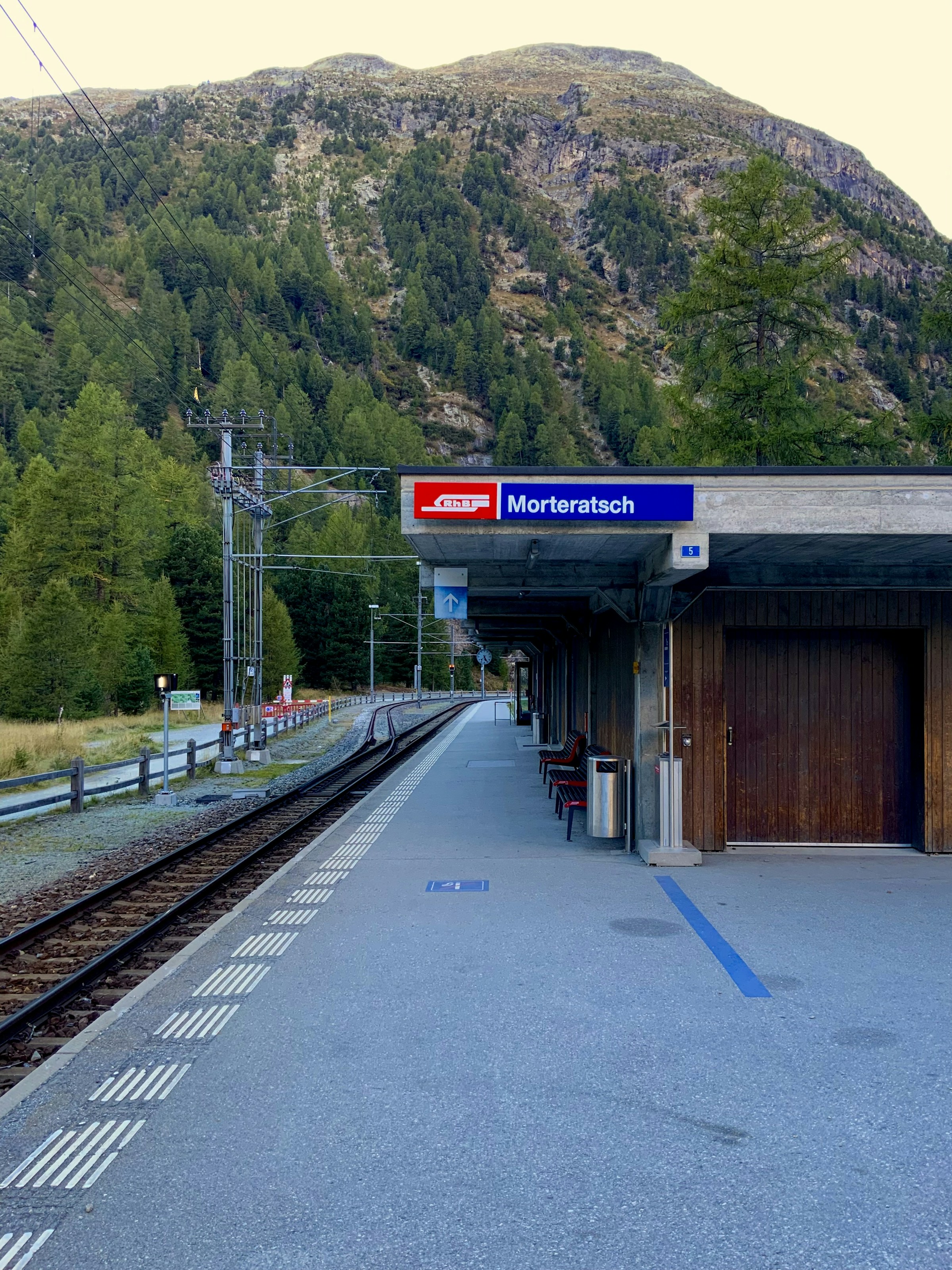 Morteratsch railway platform beneath a wooded mountainside in Pontresina; archive photograph